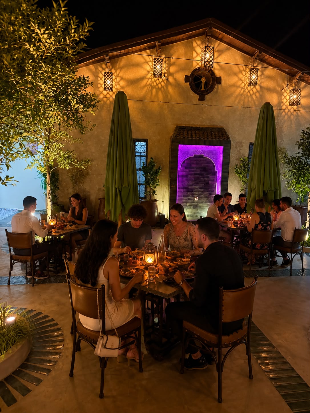 Convives dans le patio éclairé par les lanternes à la tombée de la nuit
